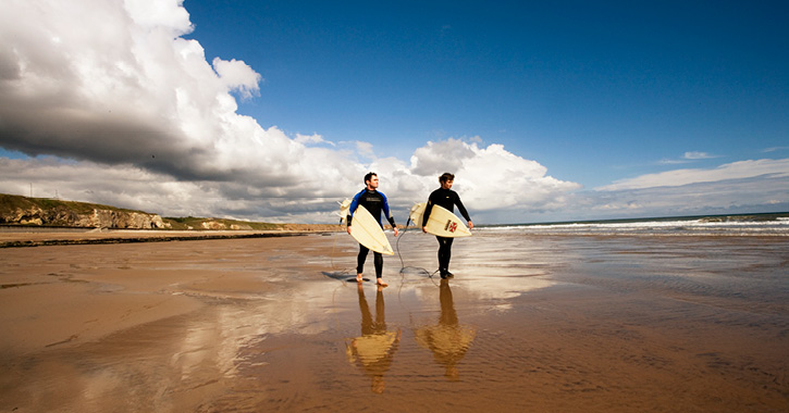 two surfers walking towards sea at Seaham Beach, County Durham.